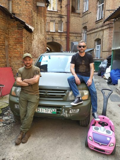Jeden z nejznámějších současných ukrajinských spisovatelů Serhij Žadan (na obrázku vpravo) je nyní hlavně motorem projektu, který má za cíl vybrat peníze na 100 aut pro ukrajinskou armádu. Vyhlásil ho v létě, na fotografii sedí na kapotě auta číslo 6, ve druhé polovině listopadu se ale dostal už na 77! Zdroj: facebooková stránka Serhije Žadana